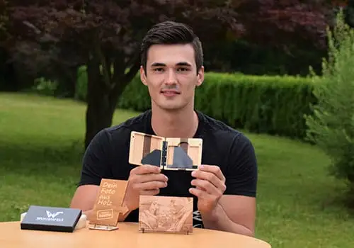 Dominik Pototschnig at a garden table with a wooden wallet and photo engravings on wood