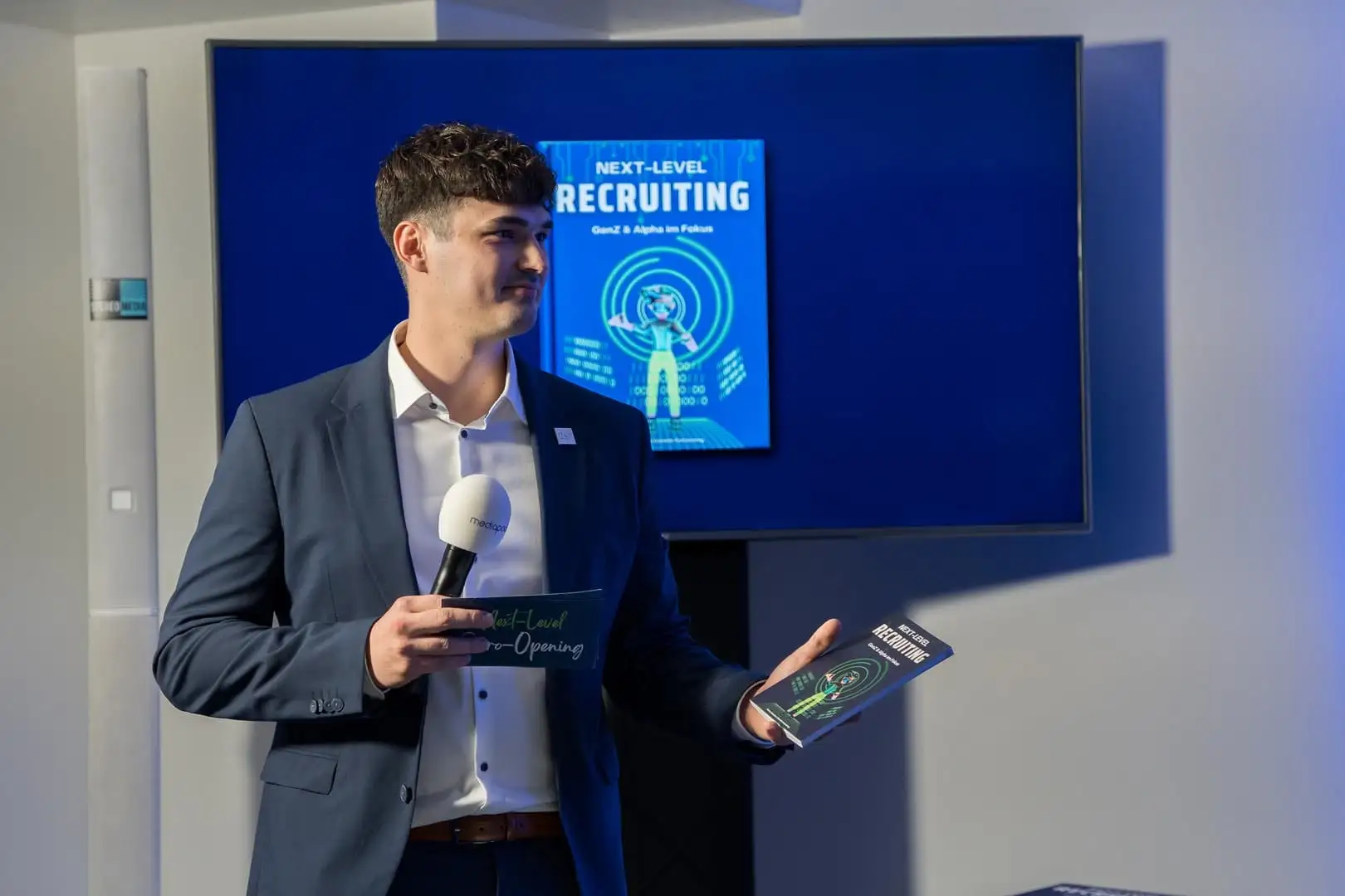 Dominik Pototschnig holding a microphone and the book “Next-Level Recruiting” at an event