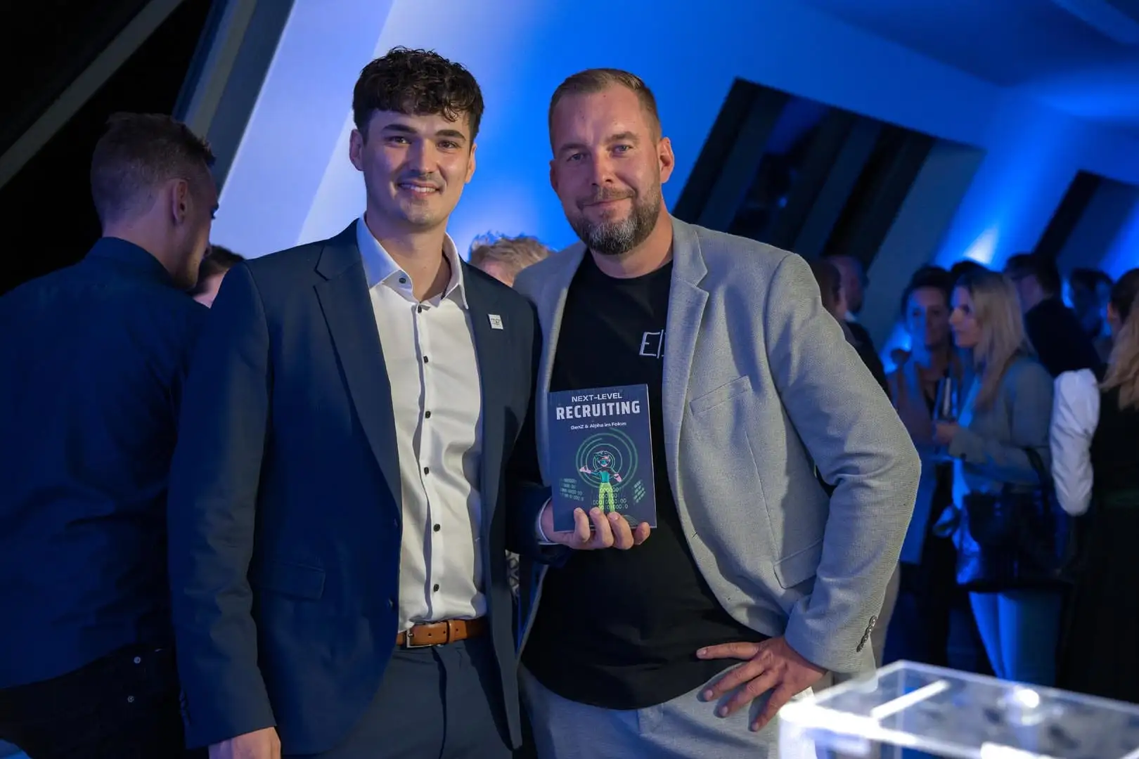 Dominik Pototschnig at an evening event holding the book “Next-Level Recruiting”