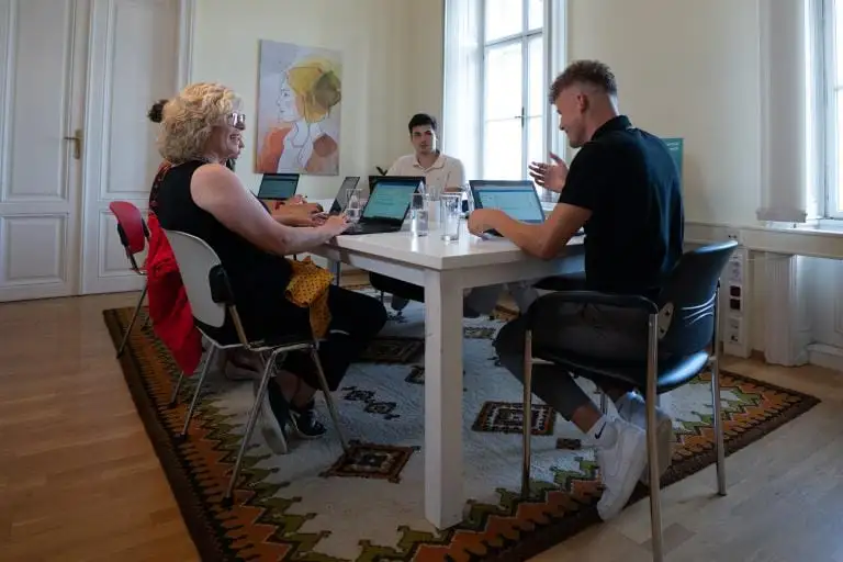 Consulting session at a bright meeting table, three people working together on laptops